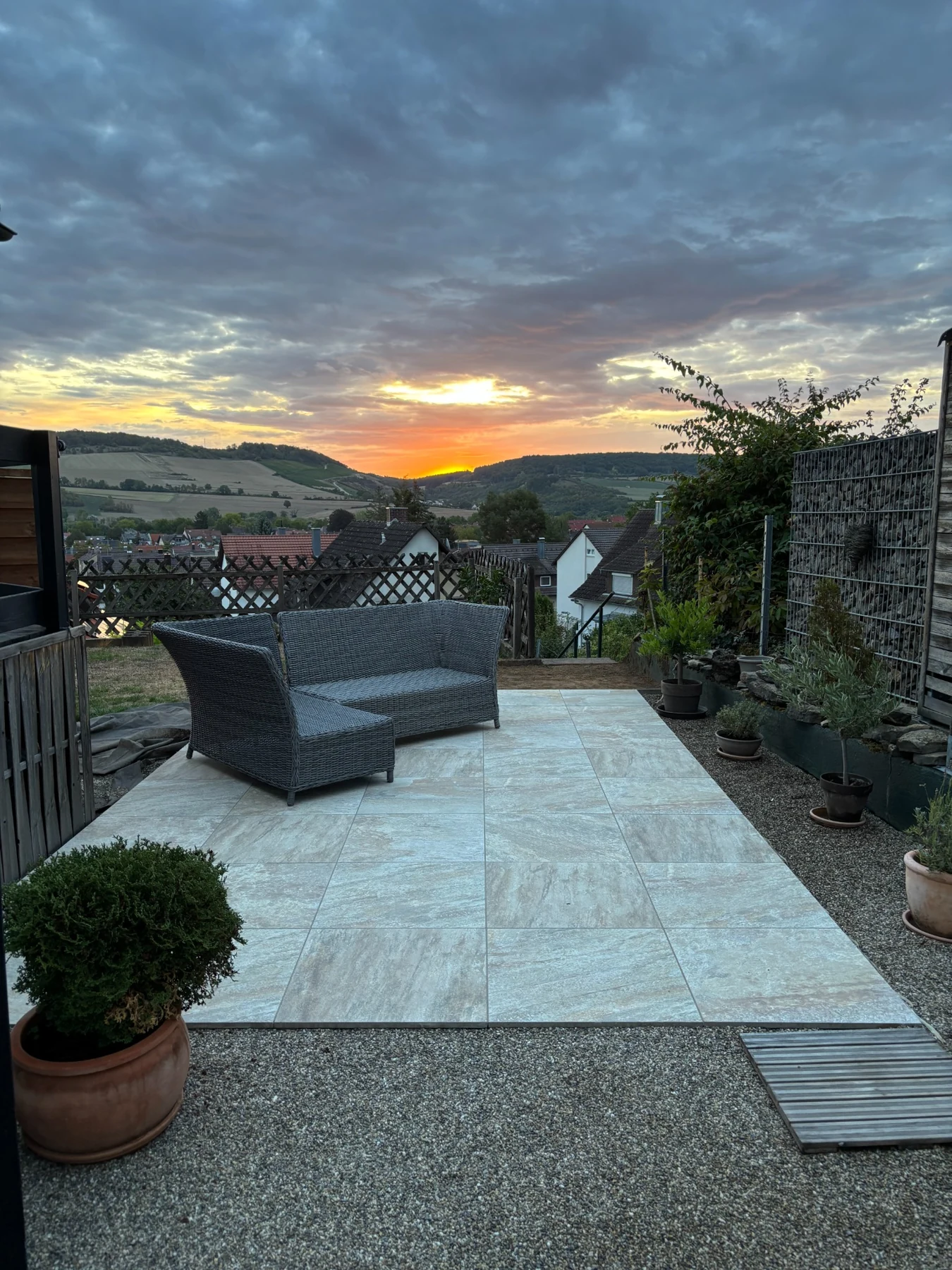Terrasse mit großformatigen Platten und Sitzgruppe im Abendlicht über dem Taubertal